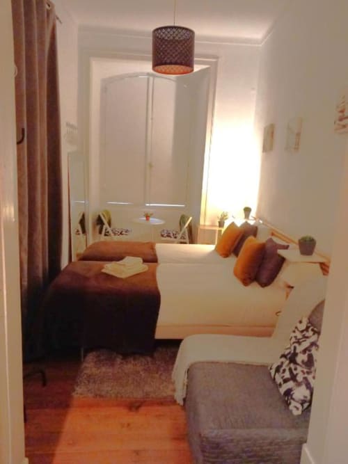 Modern bedroom in Lisbon apartment with beds, sofa, dining area, and city view window