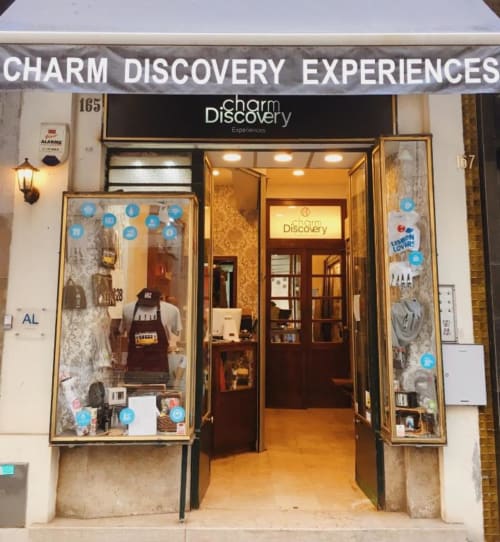 Charm Discovery Experiences storefront entrance in Lisbon, Portugal with decorated window displays and blue social media
