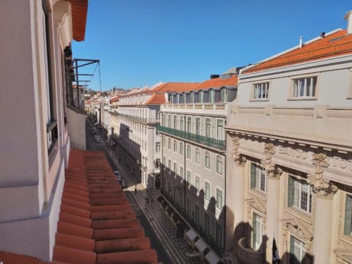 Red staircase with city view overlooking Lisbon's historic buildings and terracotta roofs from Charm Discovery Experiences