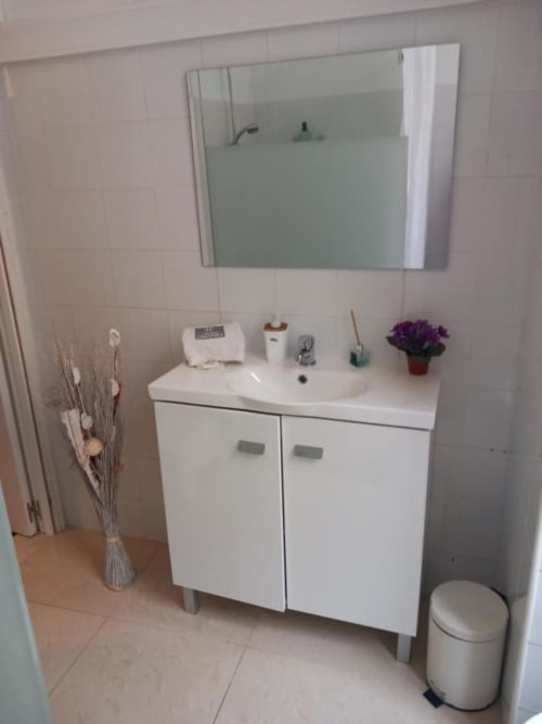 Modern bathroom in Lisbon apartment with white vanity sink, mirror, and toilet