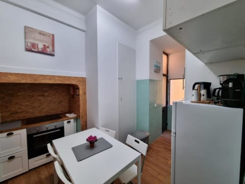 Modern kitchen and dining area in Lisbon apartment with white cabinetry, wooden accents, and city view access