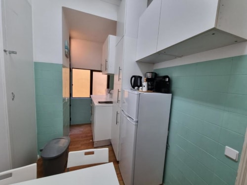 Modern kitchenette in BRAUL2 apartment at Charm Discovery Experiences, Lisbon, with white cabinets, refrigerator, and mint