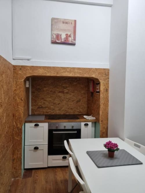 Compact kitchen with white cabinetry, black oven, and dining table in Lisbon apartment at Charm Discovery Experiences