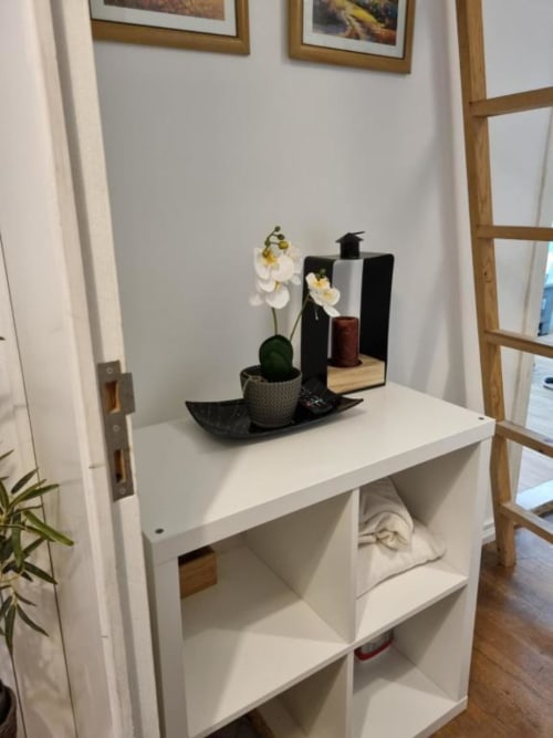 White shelving unit with decorative black tray, white orchid, and toiletries in Lisbon apartment