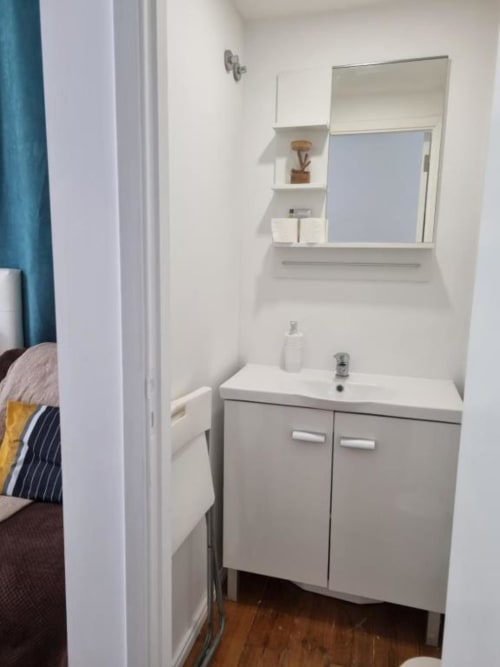 Modern bathroom with white vanity and mirror in Lisbon BnB apartment with hardwood floors and city view