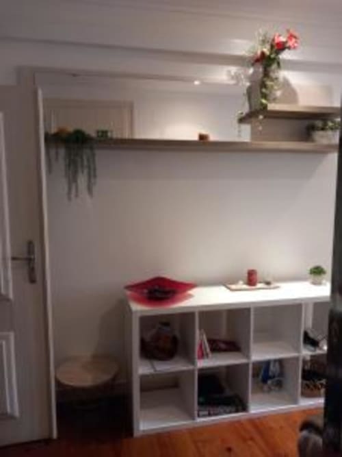 Modern Lisbon apartment entryway with white shelving, decorative flowers, and hardwood floors in Charm Discovery Experiences