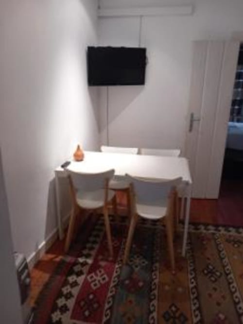 Dining area in Lisbon apartment with white table, wooden chairs, and wall-mounted TV