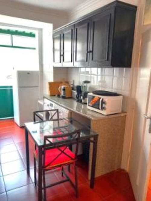 Modern kitchen with black cabinets, dining table and red chairs at Charm Discovery Experiences Lisbon apartment