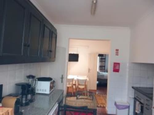 Kitchen and dining area of Two-Bedroom Apartment at Charm Discovery Experiences in Lisbon with dark cabinets and hardwood