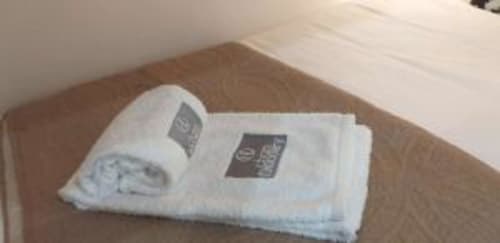 Folded white towels with hotel branding on wooden table in Lisbon apartment C165-2