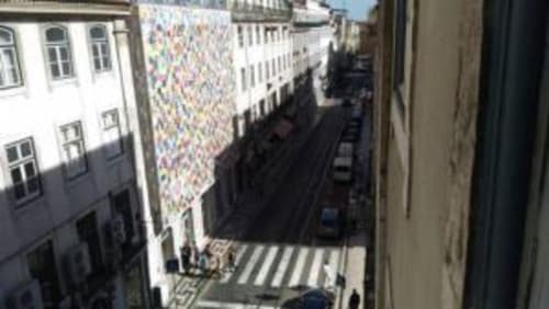 Lisbon street view from C165-2 apartment with colorful street art, historic buildings, and pedestrian crossing below