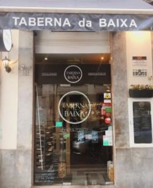 Taberna da Baixa restaurant storefront entrance in Lisbon with illuminated signage and dark interior visible through glass