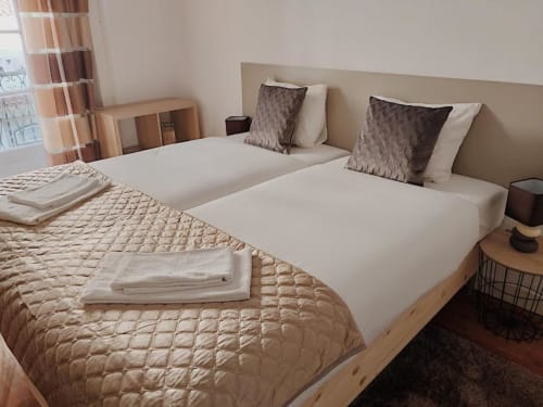 Twin beds with white linens and decorative pillows in a modern Lisbon apartment at Charm Discovery Experiences