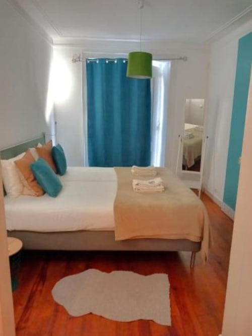 Modern bedroom at Charm Discovery Experiences Lisbon apartment with teal accents, wooden floors, and ensuite bathroom