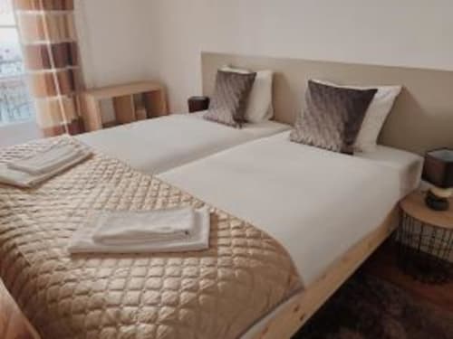 Modern two-bedroom apartment at Charm Discovery Experiences in Lisbon with twin beds, neutral bedding, and striped curtains