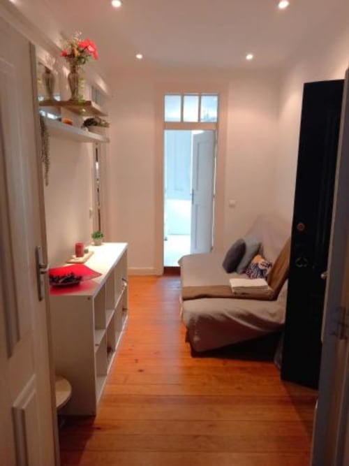 Modern Lisbon apartment entryway with wooden floors, white vanity, red flowers, and living area at Charm Discovery