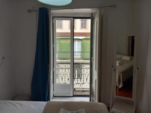 Bright bedroom in Lisbon apartment with French doors opening to balcony overlooking city street