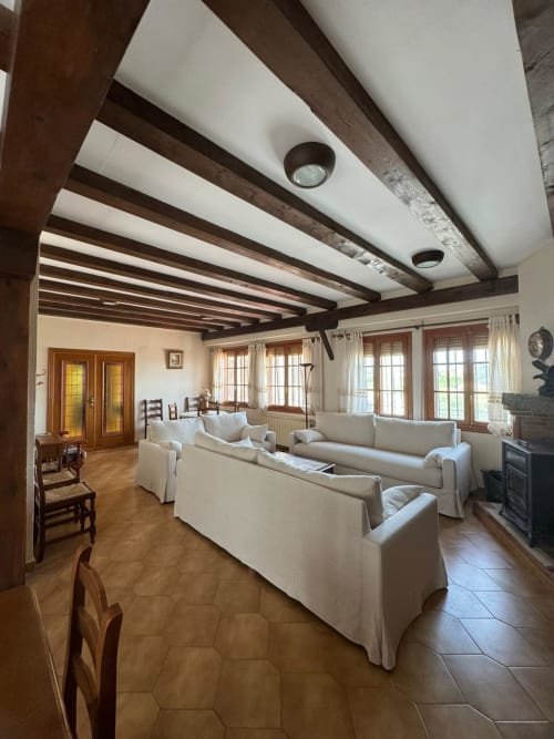 Spacious living room at Casa Rural Finca El Olivar cottage with cream sofas, exposed wooden beams, terracotta floors, and