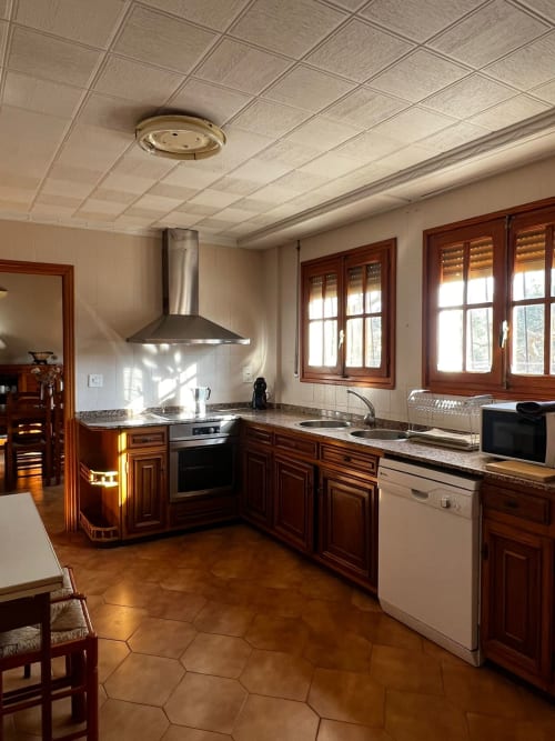 Spacious kitchen in Casa Rural Finca El Olivar cottage with wood cabinetry, stainless steel appliances, and terracotta tile
