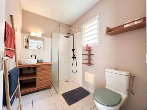 Salle de bain moderne de la villa Goyave aux Exotic Villas Martinique avec douche à l'italienne, meuble vasque en bois, toilettes et murs roses