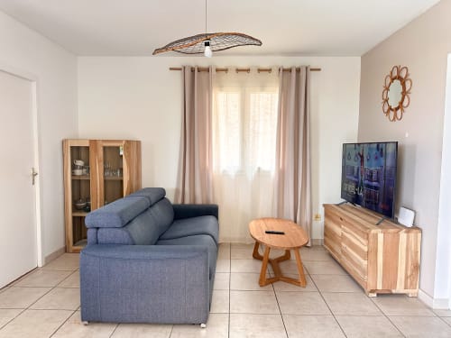 Salon moderne de la villa Goyave aux Exotic Villas Martinique au Diamant, avec canapé bleu, mobilier en bois et TV écran plat