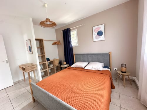 Chambre moderne de la villa Goyave aux Exotic Villas Martinique avec literie orange, tête de lit grise, mobilier en bois et ambiance chaleureuse