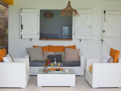 Lounge extérieur moderne aux Exotic Villas Martinique avec mobilier en rotin blanc, touches orange et vue sur mer à Le Diamant