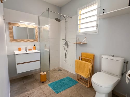 Salle de bain moderne de la villa Ananas aux Exotic Villas Martinique avec douche à l'italienne, vasque blanche et finitions dorées