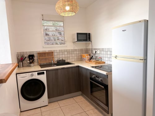 Cuisine compacte à la villa Ananas des Exotic Villas Martinique avec électroménagers blancs, armoires foncées et dosseret en carrelage au
