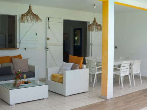Espace de vie moderne avec mobilier en rotin blanc, accents orangés et lumière naturelle à la villa Exotic Villas Martinique