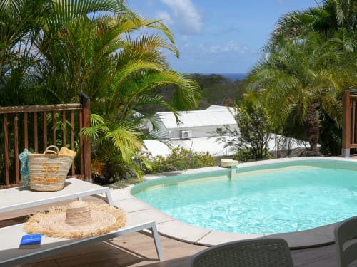 Piscine turquoise entourée de palmiers aux Exotic Villas Martinique au Diamant, vue sur mer et transats