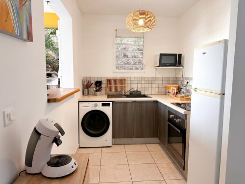 Cuisine moderne de la villa Ananas aux Exotic Villas Martinique avec lave-linge, cuisinière, réfrigérateur et suspension en rotin