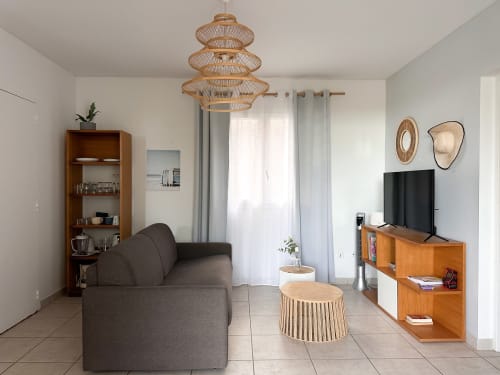 Villa moderne avec salon, canapé gris, mobilier en bois, suspension tissée et vue sur mer aux Villas Exotiques Martinique