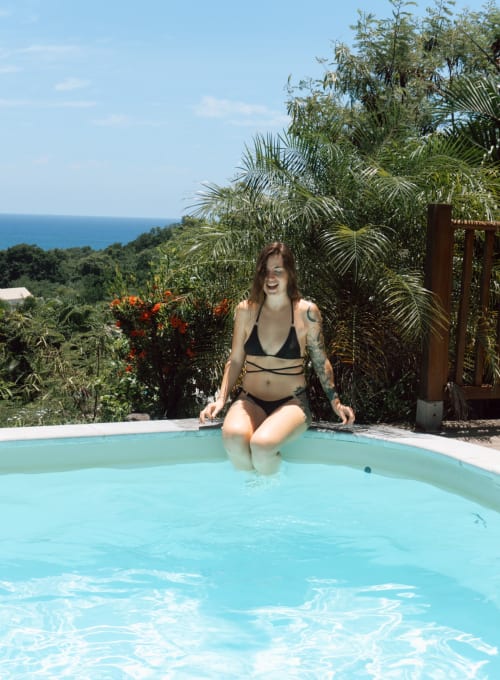 Femme à la piscine des Exotic Villas Martinique avec vue sur l'océan, végétation tropicale et palmiers à Le Diamant