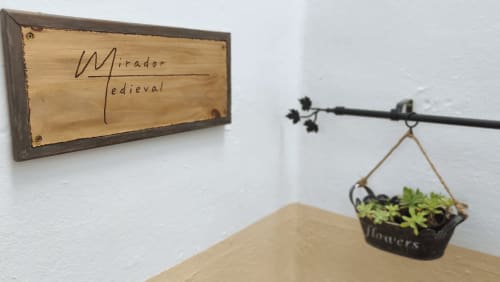 Apartamento Mirador Medieval en Cáceres con cartel decorativo de madera y cesta de flores colgante en soporte metálico