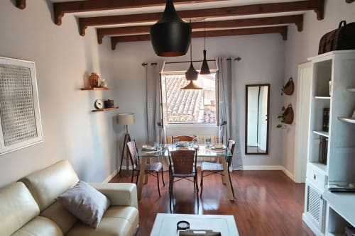 Moderno salón comedor en Cáceres, España - vigas de madera, lámparas colgantes y vistas a tejas de barro