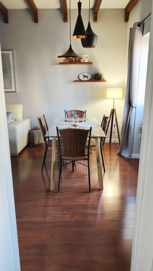 Comedor moderno en apartamento Mirador Medieval, Cáceres con suelos de madera, lámparas colgantes y sillas tejidas