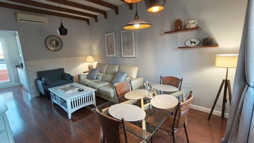 Salón moderno del apartamento Mirador Medieval en Cáceres con comedor, zona de estar, lámparas colgantes y suelos de madera