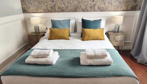 Habitación moderna del hotel Mirador Medieval en Cáceres con acentos turquesa, almohadas amarillas, camas gemelas y toallas organizadas