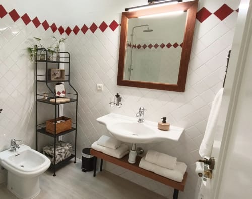 Cuarto de baño moderno en Mirador Medieval de Cáceres con azulejos metro blancos, detalles burdeos, lavamanos tipo recipiente y espejo con marco de madera