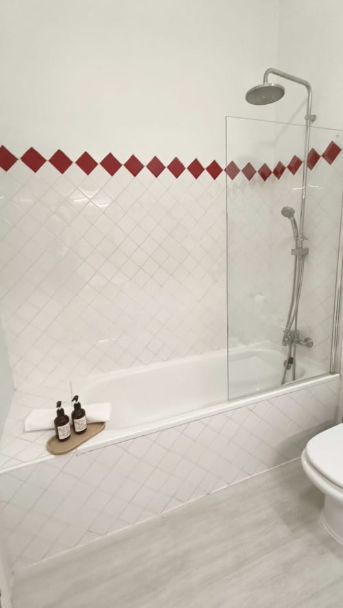 Moderno baño con ducha, azulejos de diamante rojo y accesorios cromados en el apartamento Mirador Medieval, Cáceres