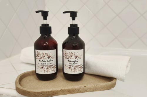 Amenidades de baño en Mirador Medieval: botellas de gel corporal y champú en bandeja de corcho con toallas