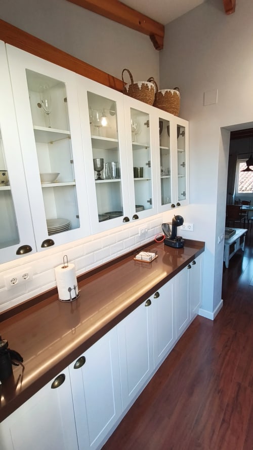 Cocina moderna con alacenas de cristal y encimera de madera en el apartamento Mirador Medieval, Cáceres