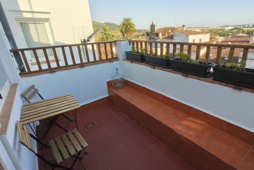 Terraza del apartamento Mirador Medieval en Cáceres con barandillas de madera, asientos y vistas panorámicas del casco histórico