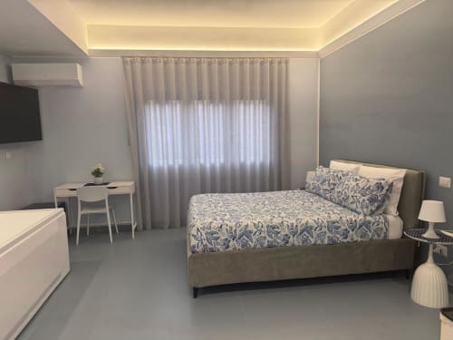 Camera moderna BellDuomo Suite Messina con letto matrimoniale, scrivania, TV, tende leggere con vista su Messina.