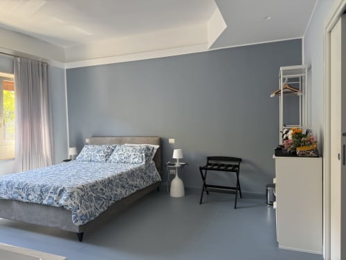 Camera moderna della BellDuomo Suite Messina con pareti azzurro-grigie, letto matrimoniale e arredamento minimalista
