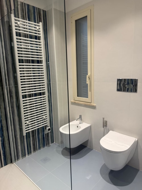 Bagno moderno della BellDuomo Suite Messina con sanitari bianchi, scaldasalviette e doccia con piastrelle blu