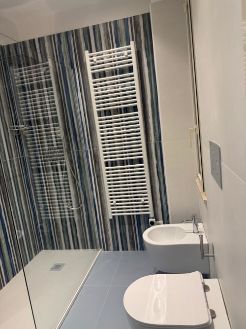 Bagno moderno della BellDuomo Suite Messina con doppio lavabo, piastrelle a righe, scaldasalviette e doccia walk-in
