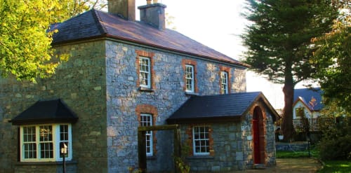 Knockaderry House stone cottage B&B in Ennis, Ireland with slate roof and green-framed windows surrounded by trees