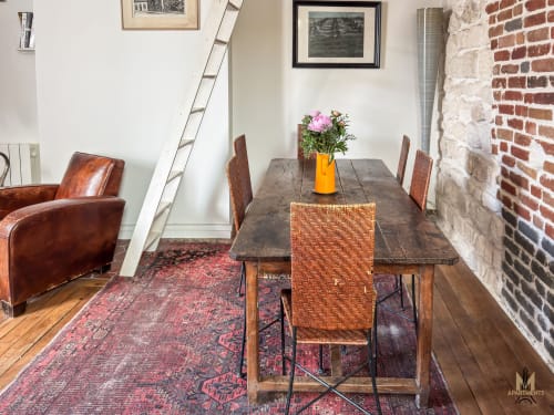 Salle à manger de l'appartement Del Sarte aux Appartements Montmartre Paris avec table en bois, chaises tissées, fleurs roses et poutres apparentes